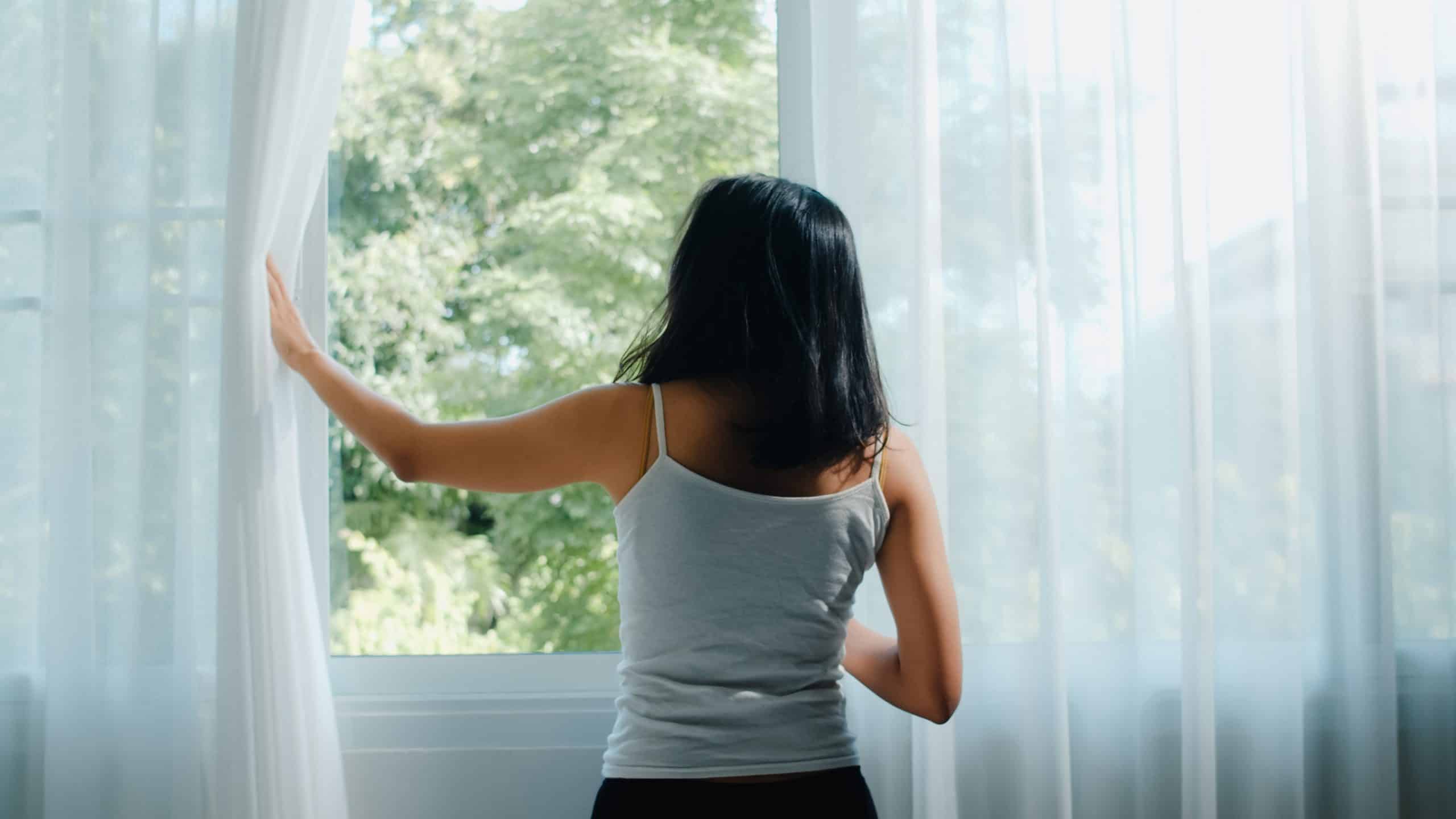 mujer abre la ventana en la mañana